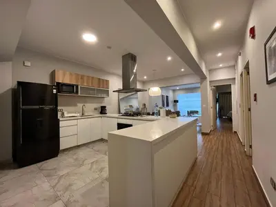 a large kitchen with white cabinets and a black refrigerator at MLA apartments - Larcomar in Lima