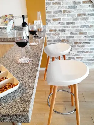 two white stools sitting on a kitchen counter with wine glasses at Stylish New Apartment with stunning Ocean View near Miraflores in Lima