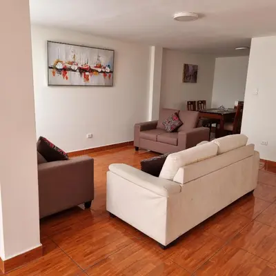a living room with a white couch and two chairs at Apart Hotel Cabral in Lima
