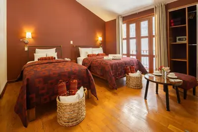 a hotel room with two beds and a table at Mamasara Cusco in Cusco
