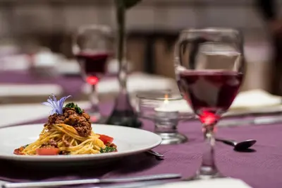 a plate of pasta on a table with a glass of wine at Mamasara Cusco in Cusco