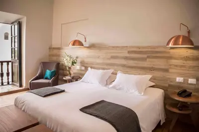 a bedroom with a large white bed and a chair at Abittare Hotel in Cusco