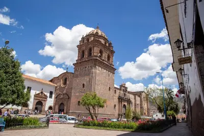 a church with a tall tower in front of a building at Abittare Hotel in Cusco