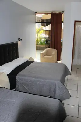 a bedroom with two beds and a chair and a window at Embassy Beach in Pisco