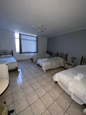 a room with three beds and a ceiling fan at Embassy Beach in Pisco