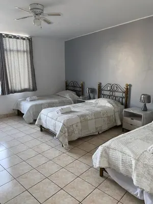 a bedroom with three beds and a ceiling fan at Embassy Beach in Pisco