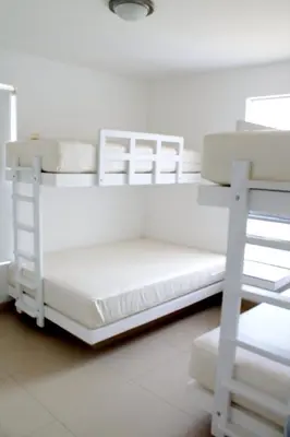 two bunk beds in a white room with a ladder at Casa 33 Sotavento Paracas in Paracas