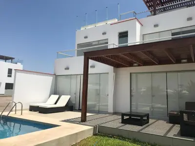 a house with a swimming pool and a patio at Casa 33 Sotavento Paracas in Paracas