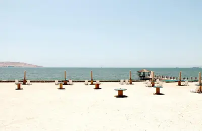 a row of tables and benches on the beach at Casa 33 Sotavento Paracas in Paracas