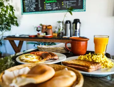 a table with plates of breakfast foods and a drink at Eco Home View - Guest House in Cusco