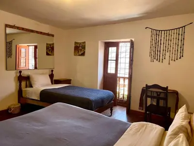 a bedroom with two beds and a chair and a mirror at Eco Home View - Guest House in Cusco