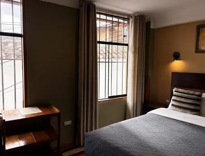 a bedroom with a bed and two windows at Eco Home View - Guest House in Cusco