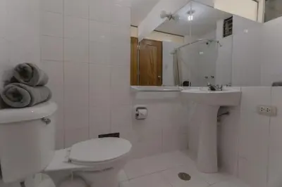 a white bathroom with a toilet and a sink at Quechua ApartHotel in Cusco