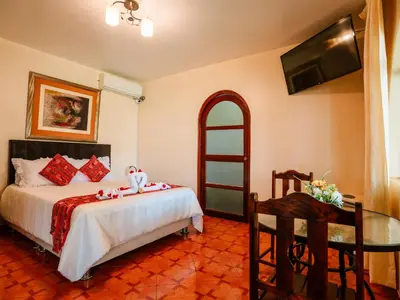a bedroom with a bed and a table and a television at Hotel Viñas del Sol Eterno in Chincha Alta