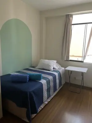 a bedroom with a bed with a blue blanket and a window at Hermoso departamento en pueblo libre cerca al aeropuerto in Lima