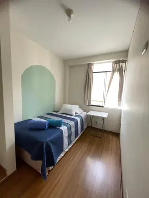 a bedroom with a bed with blue sheets and a window at Hermoso departamento en pueblo libre cerca al aeropuerto in Lima