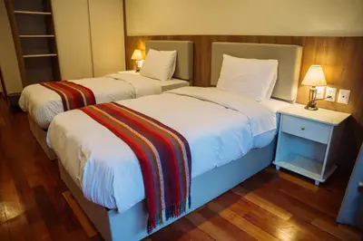 two beds in a hotel room with at Tikawasi ollanta 2 incluye transporte o recojo a la estacion de tren in Ollantaytambo