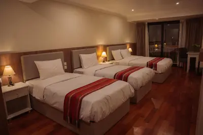 a hotel room with two beds and a table at Tikawasi ollanta 2 incluye transporte o recojo a la estacion de tren in Ollantaytambo