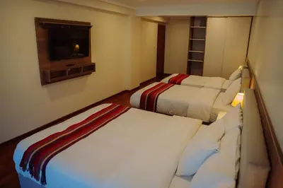 a hotel room with two beds and a tv at Tikawasi ollanta 2 incluye transporte o recojo a la estacion de tren in Ollantaytambo