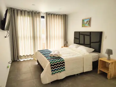 a bedroom with a large bed and a large window at Jalara hotel Boutique Lunahuaná in Lunahuaná