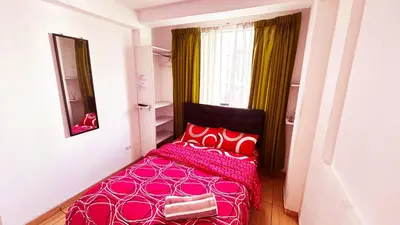 a bedroom with a pink bed with red pillows at I Relajante Habitación en Miraflores Central in Lima