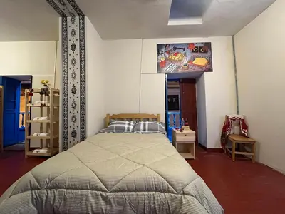 a bedroom with a bed and a tv on the wall at The Sleepy Mouse in Cusco