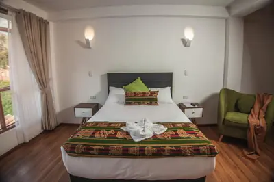 a bedroom with a large bed and a green chair at Florez de la Villa in Huaran