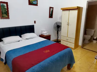 a bedroom with a bed and a bathroom with a fan at Hotel los angeles in Huaral