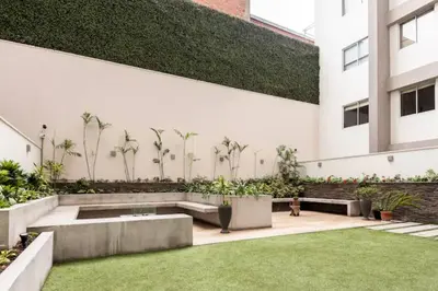a courtyard of a building with a bench and grass at Lindo y Espacioso Departamento muy cerca a Miraflores in Lima