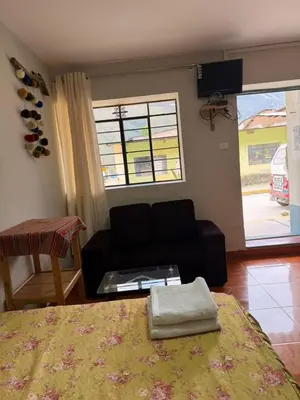 a bedroom with a bed and a couch and a window at Hospedaje Quillabamba in Santa Teresa