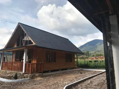 a large wooden house with mountains in the background at Cabañas - Kobold Haus in Oxapampa