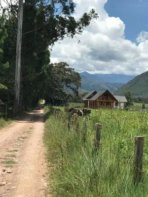 a dirt road next to a field with a barn at Cabañas - Kobold Haus in Oxapampa