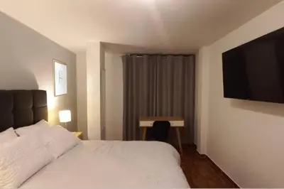 a hotel room with a bed and a flat screen tv at Gorgeous Private Studio LIMA-Own Bathroom-Near Airport in Lima