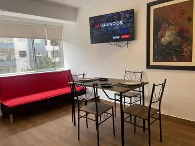 a dining room with a red couch and a table and chairs at 14 Departamento acogedor y nuevo en Miraflores in Lima