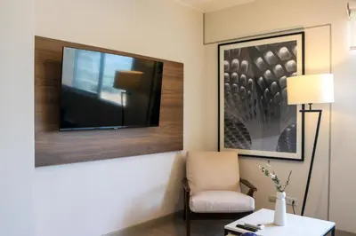 a room with a chair and a television on a wall at Black by Wynwood House in Lima