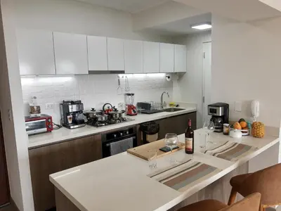 a kitchen with white cabinets and a counter with a bottle of wine at Encantador apartamento en Miraflores in Lima