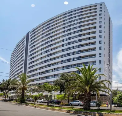 a large white building with palm trees in front of it at Encantador apartamento en Miraflores in Lima