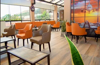 a waiting room with orange chairs and tables at COSMOPOLITAN INN in Ventanilla