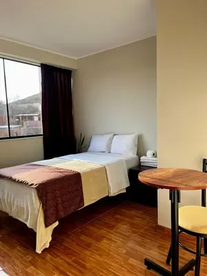 a bedroom with a bed and a table and a window at COSMOPOLITAN INN in Ventanilla