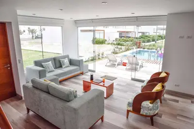 a living room with couches and chairs and a pool at Casa de playa: Disfruta de grandes momentos y del sol todo el año en Paracas in Paracas