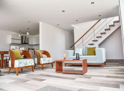 a living room with chairs and a table and stairs at Casa de playa: Disfruta de grandes momentos y del sol todo el año en Paracas in Paracas