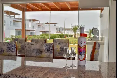 a table with two glasses and a bottle of wine at Casa de playa: Disfruta de grandes momentos y del sol todo el año en Paracas in Paracas
