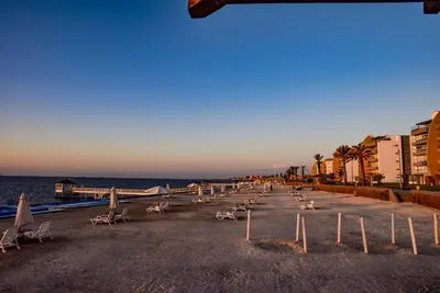 a beach with chairs and umbrellas and the ocean at Casa de playa: Disfruta de grandes momentos y del sol todo el año en Paracas in Paracas