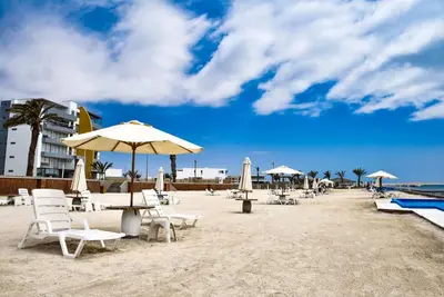 a beach with chairs and umbrellas on the sand at Casa de playa: Disfruta de grandes momentos y del sol todo el año en Paracas in Paracas