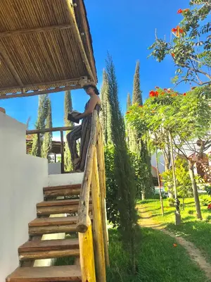 a man sitting on a wooden stairs in a garden at Casa Hotel Mamaluna in Lunahuaná