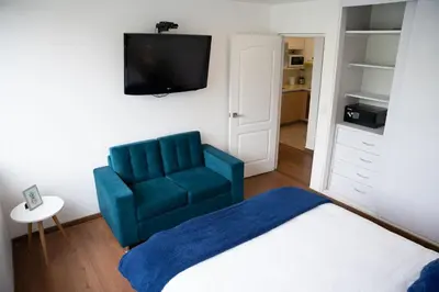 a bedroom with a blue chair and a television at Apartment in Center of Miraflores in Lima