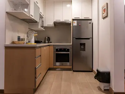 a kitchen with a stainless steel refrigerator and wooden cabinets at Apartment in Center of Miraflores in Lima