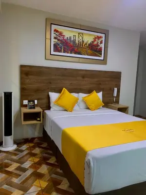 a bedroom with a large bed with yellow pillows at Cesars Hotel Lima in Lima