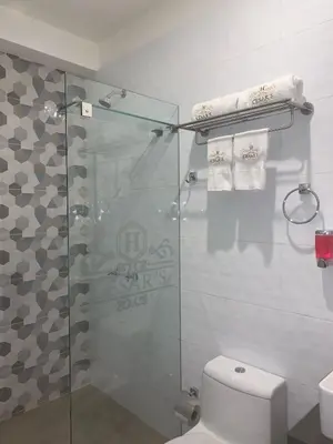 a bathroom with a shower and a toilet and towels at Cesars Hotel Lima in Lima