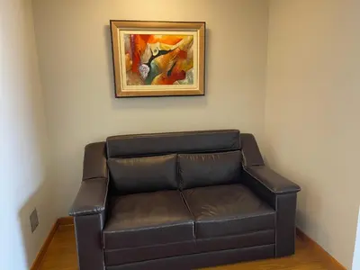 a brown leather couch in a room with a painting at Book in Miraflores - Lima in Lima